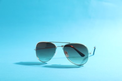 Stylish sunglasses on light blue background. Space for text