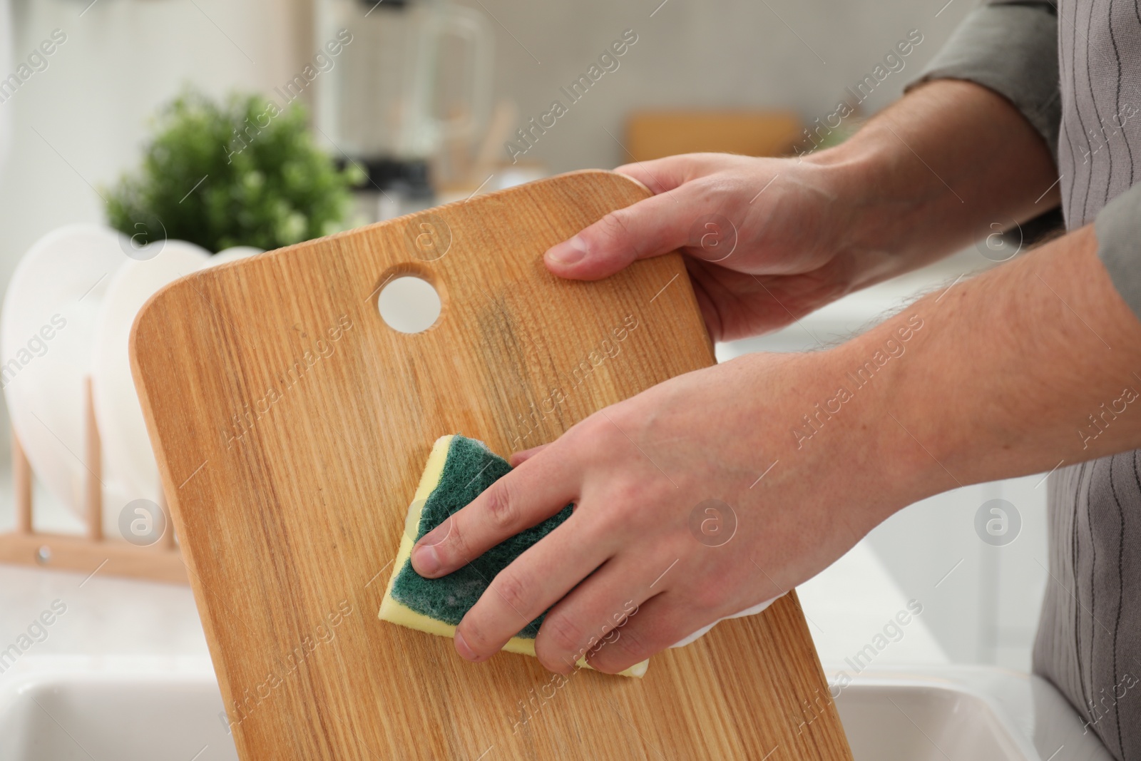 Photo of Man washing wooden cutting board in kitchen, closeup