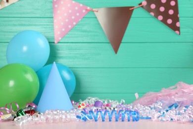 Photo of Colorful serpentine streamers and other party accessories on pink wooden table