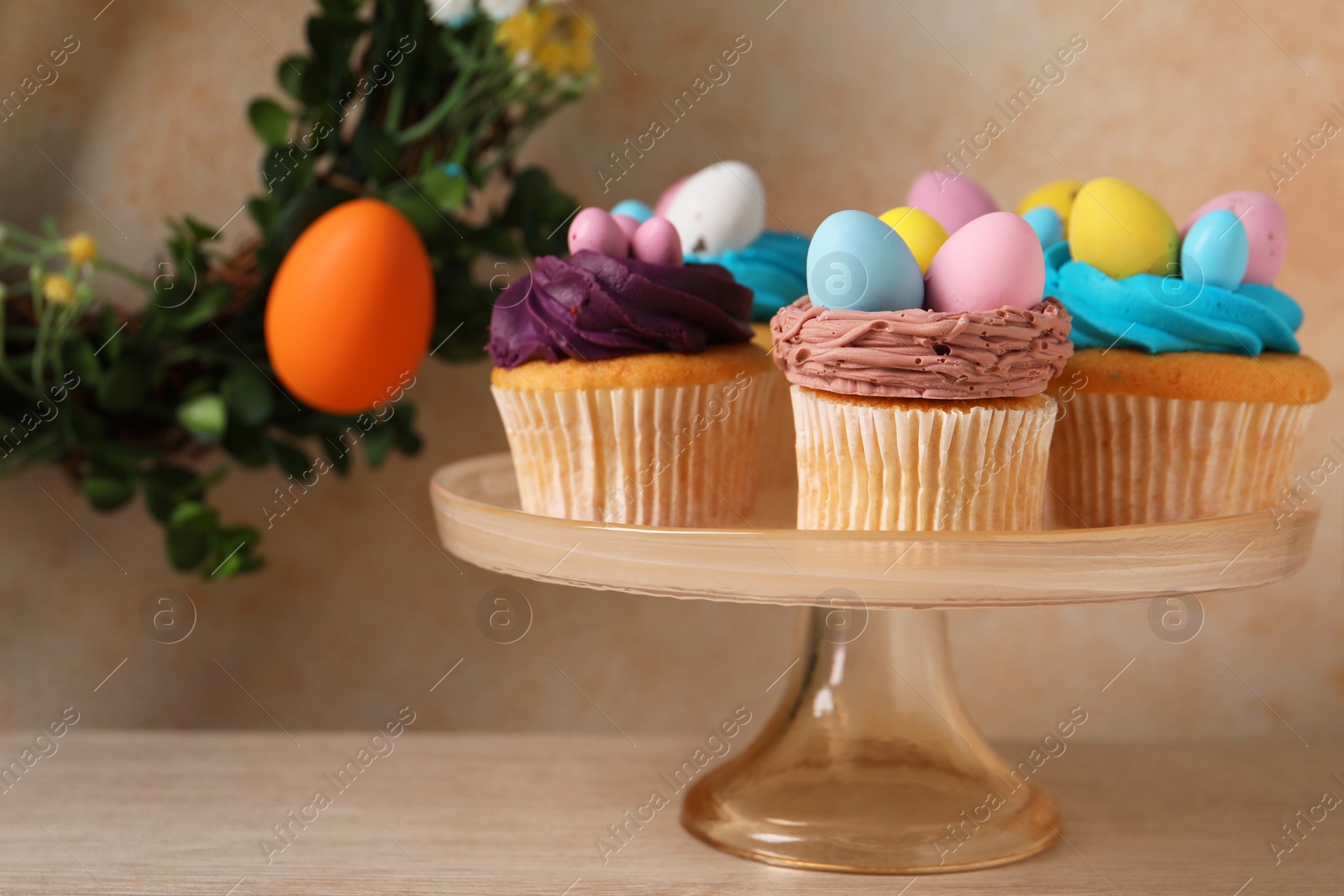 Photo of Tasty cupcakes with Easter decor on wooden table. Space for text