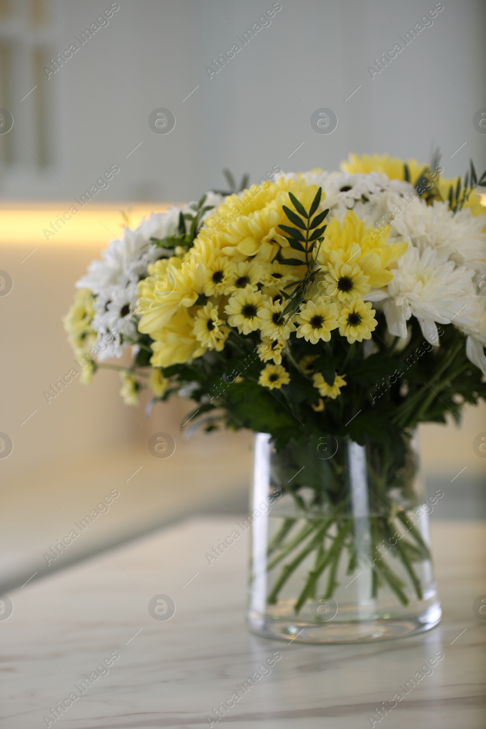 Photo of Vase with beautiful chrysanthemum flowers on table in kitchen. Interior design