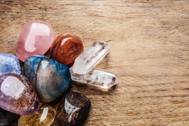 Photo of Flat lay composition with different gemstones on wooden table, space for text