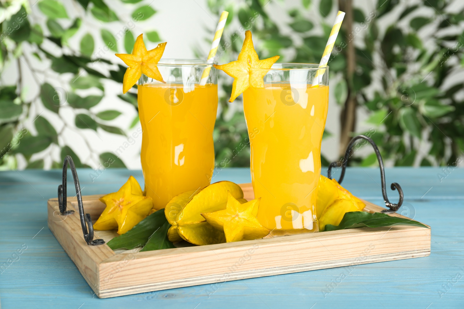 Photo of Delicious carambola juice in glasses on light blue wooden table