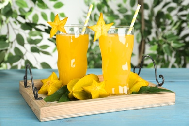 Photo of Delicious carambola juice in glasses on light blue wooden table