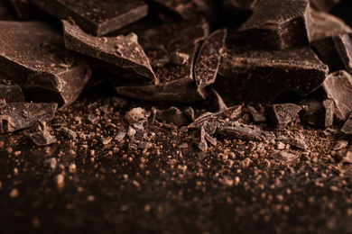 Pieces of dark chocolate on black table, closeup