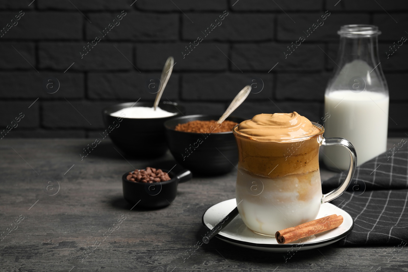 Photo of Delicious dalgona coffee and ingredients on grey table. Space for text