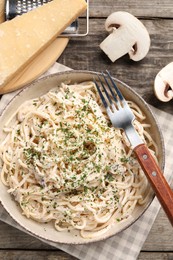 Delicious pasta with mushroom sauce and parmesan cheese on wooden table, flat lay