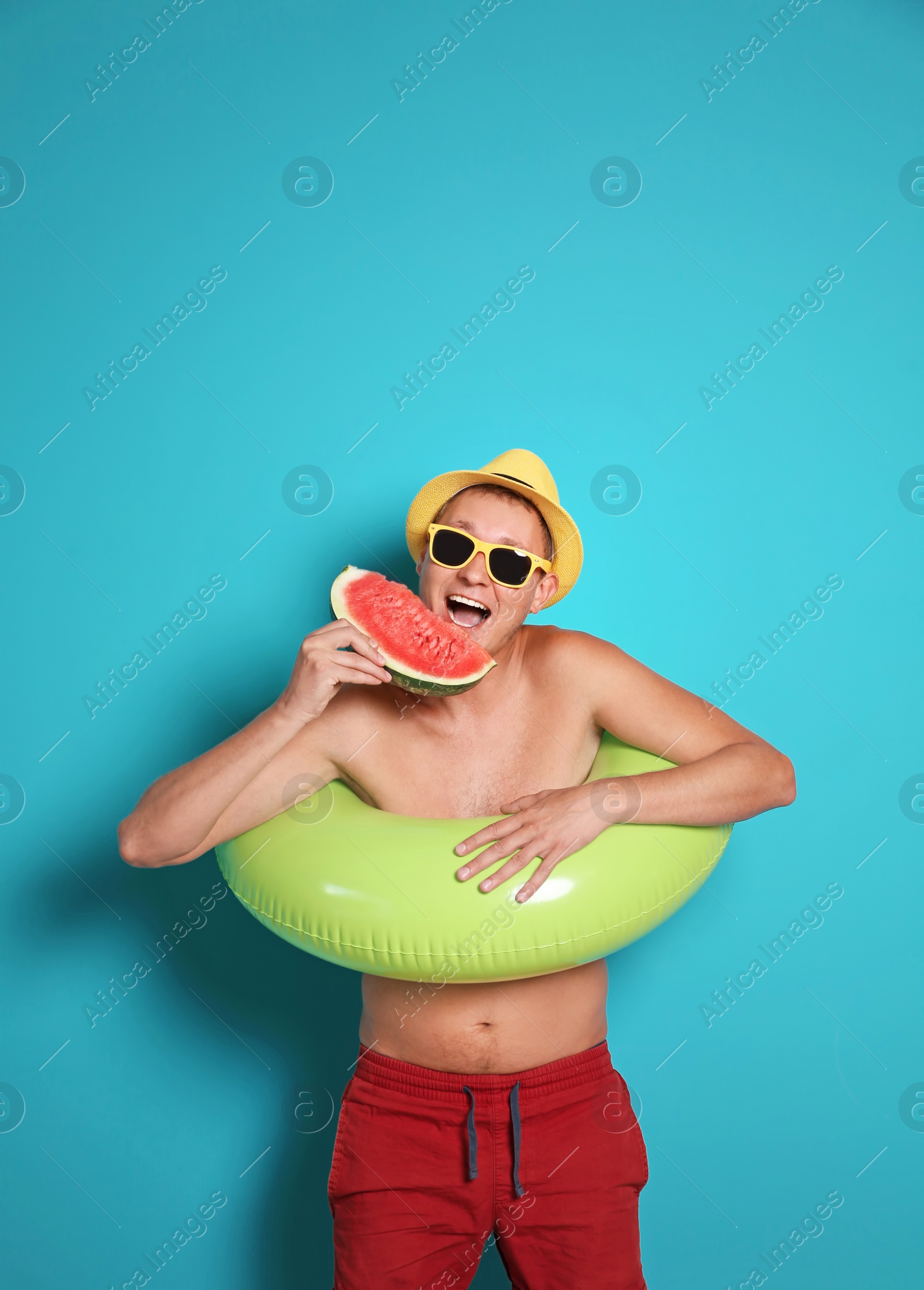 Photo of Shirtless man with inflatable ring eating watermelon on color background