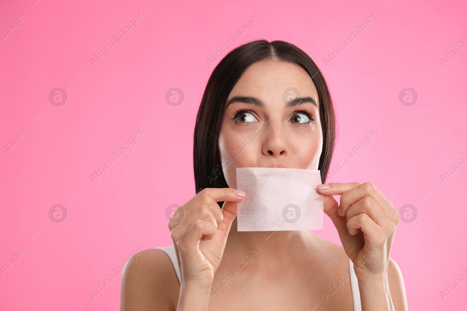 Photo of Beautiful woman using mattifying wipe on pink background