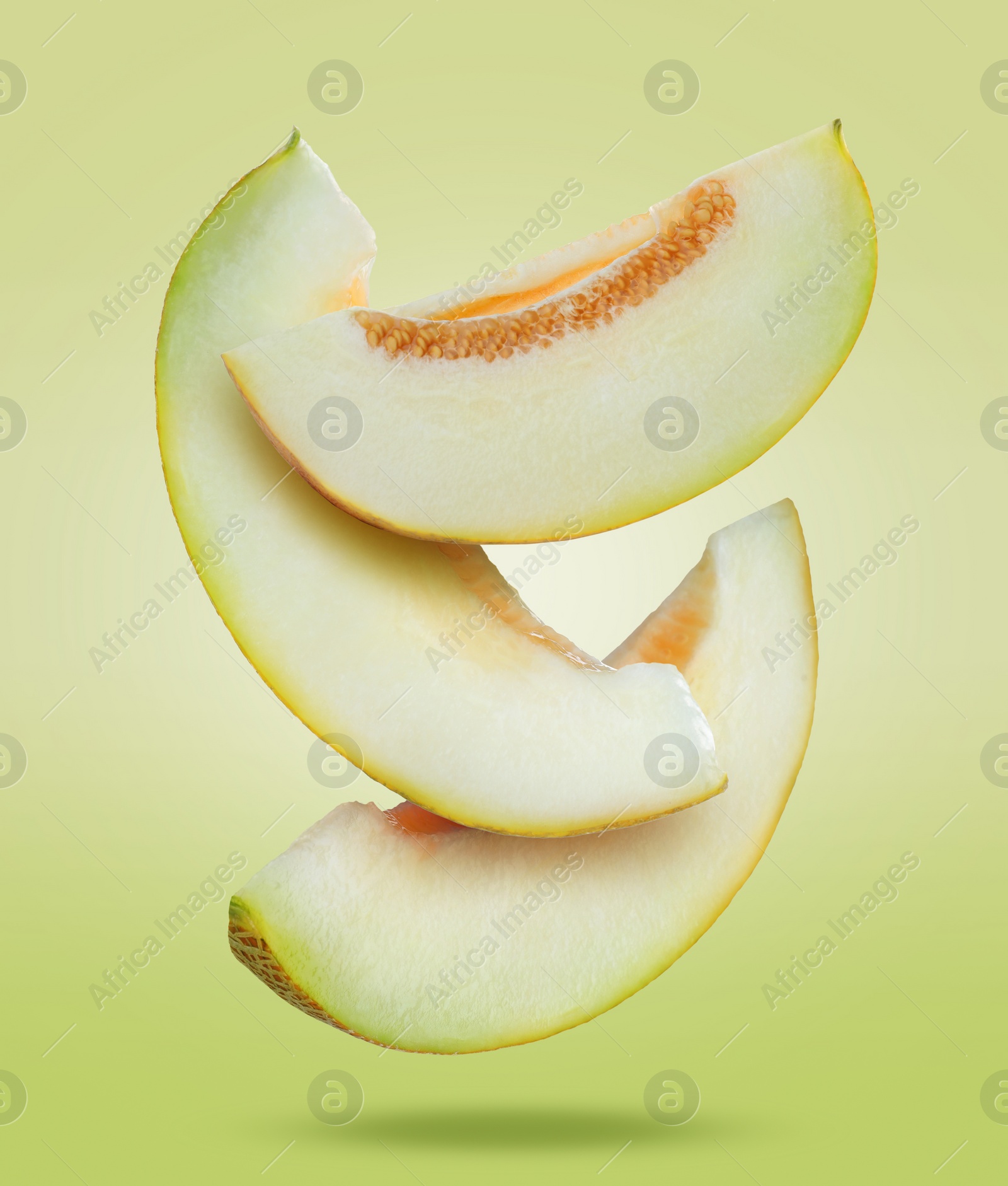 Image of Delicious ripe melon slices falling on light green background