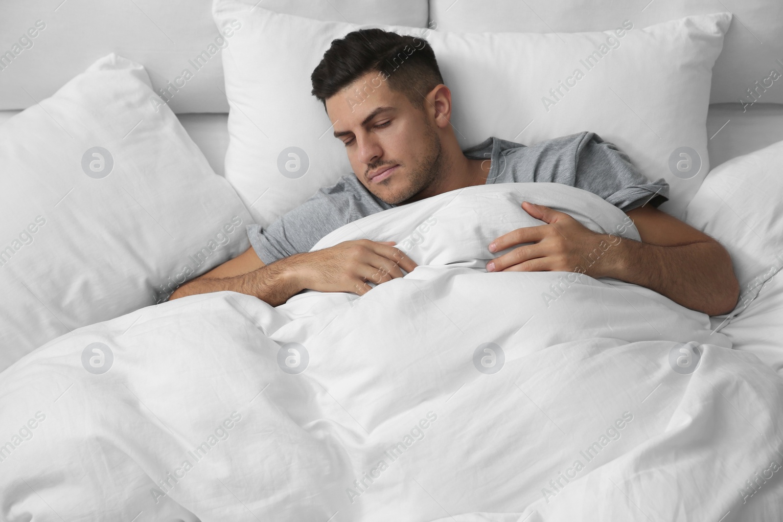 Photo of Handsome man sleeping under soft blanket in bed at home, above view