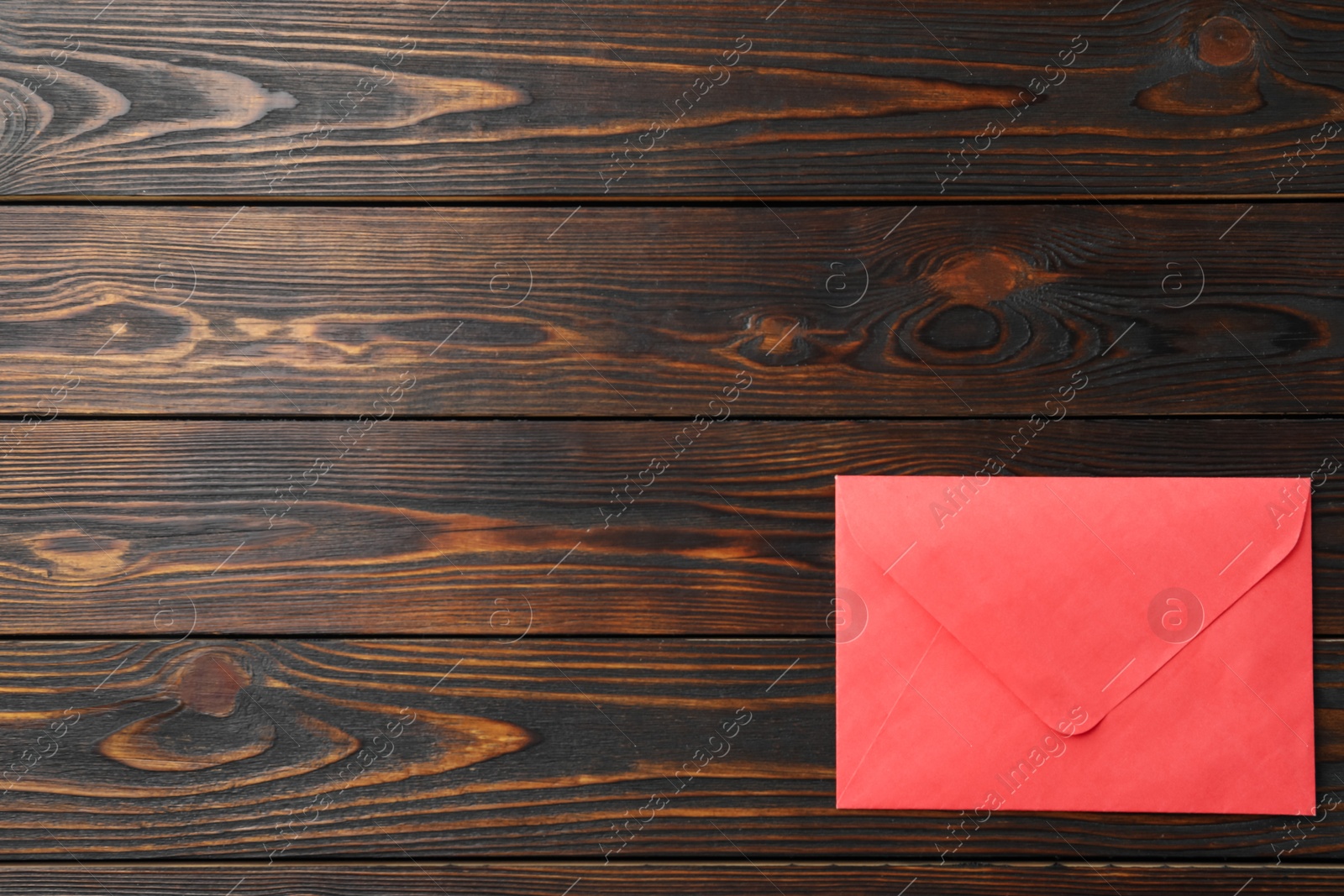 Photo of Red paper envelope on wooden background, top view. Space for text