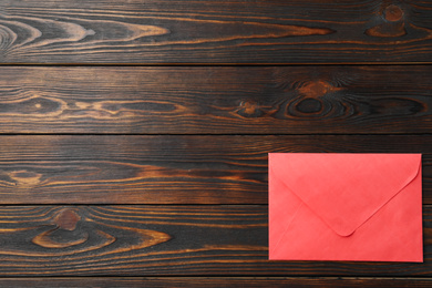 Photo of Red paper envelope on wooden background, top view. Space for text