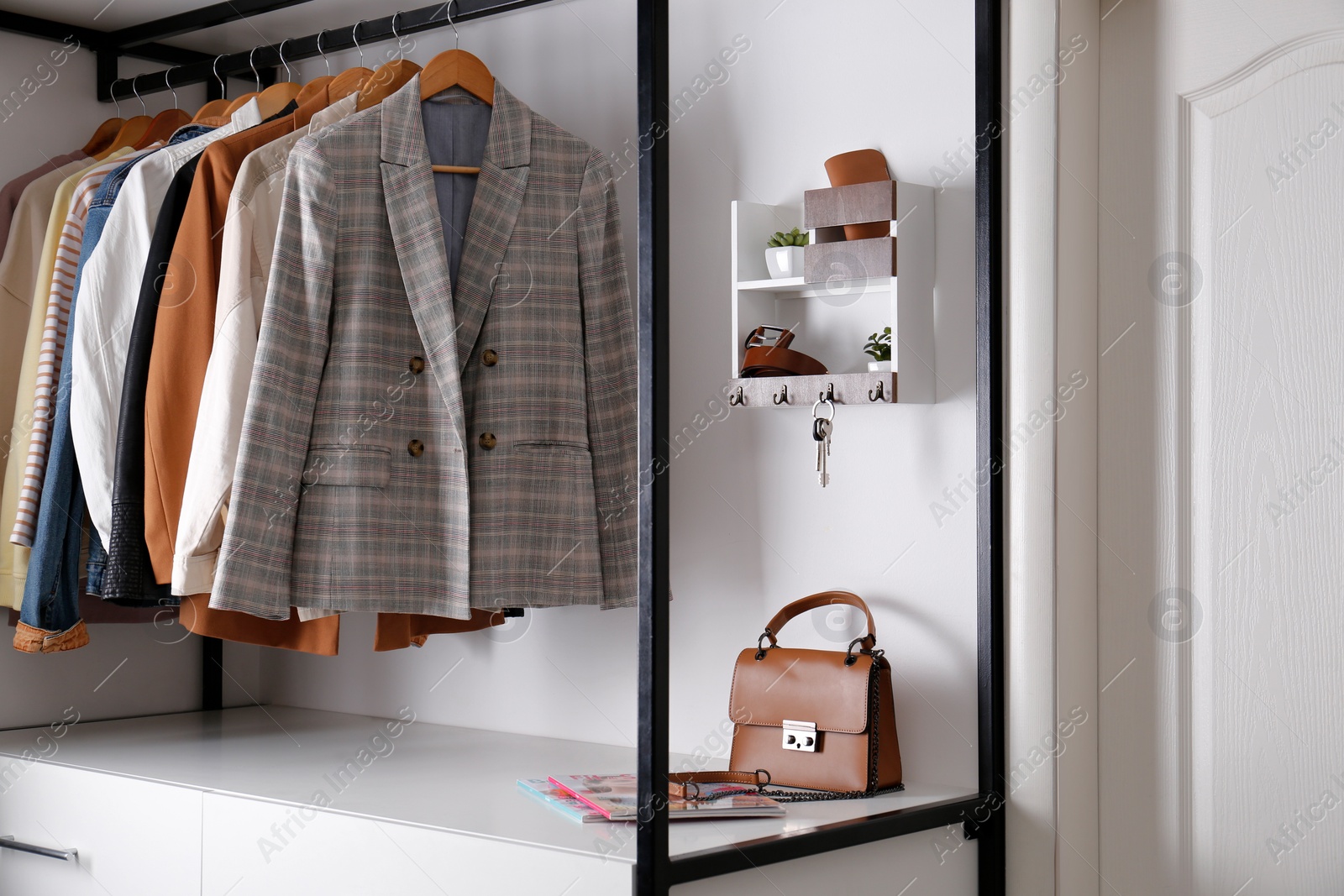 Photo of Hallway interior with stylish furniture, accessories and wooden hanger for keys on white wall