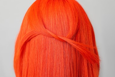 Photo of Young woman with bright dyed hair on grey background, closeup. Back view