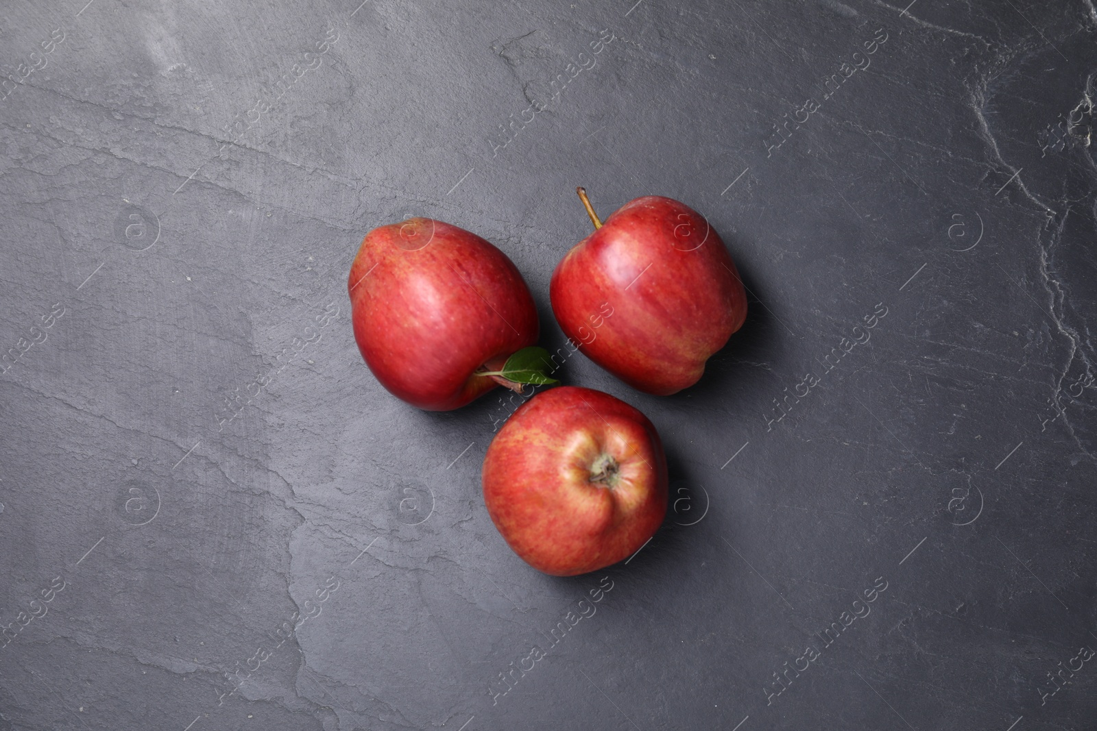 Photo of Ripe red apples on black textured table, flat lay