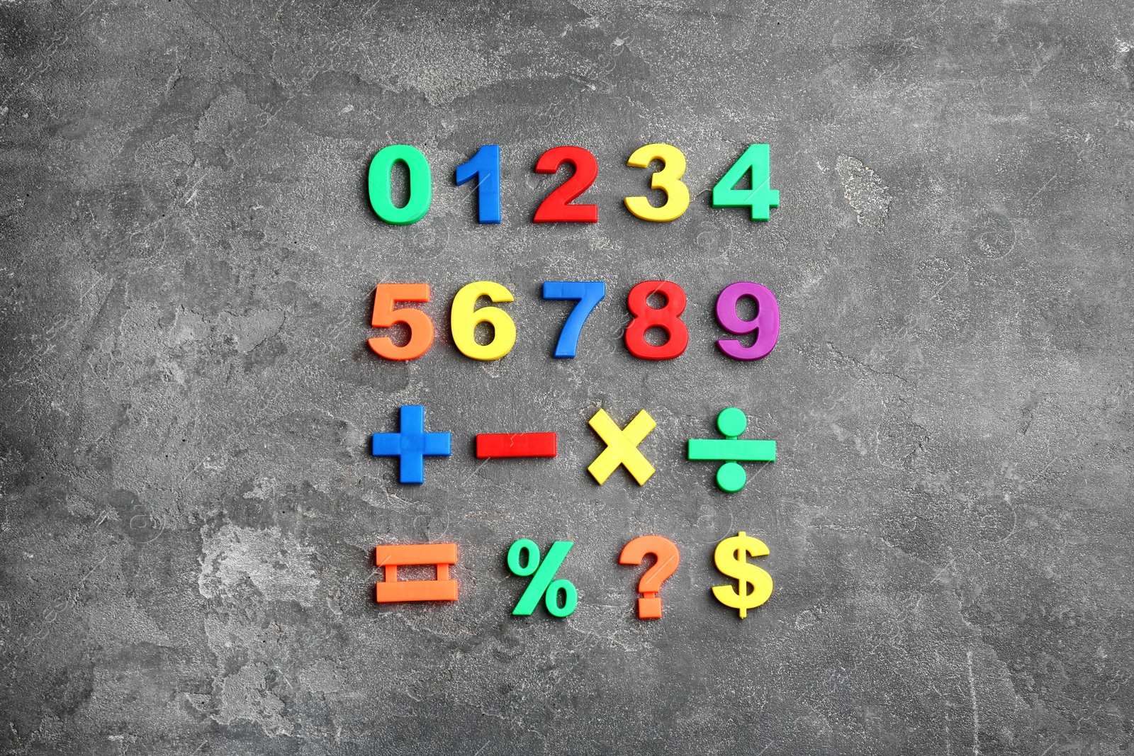 Photo of Colorful magnetic numbers and math symbols on grey stone background, flat lay