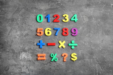 Photo of Colorful magnetic numbers and math symbols on grey stone background, flat lay