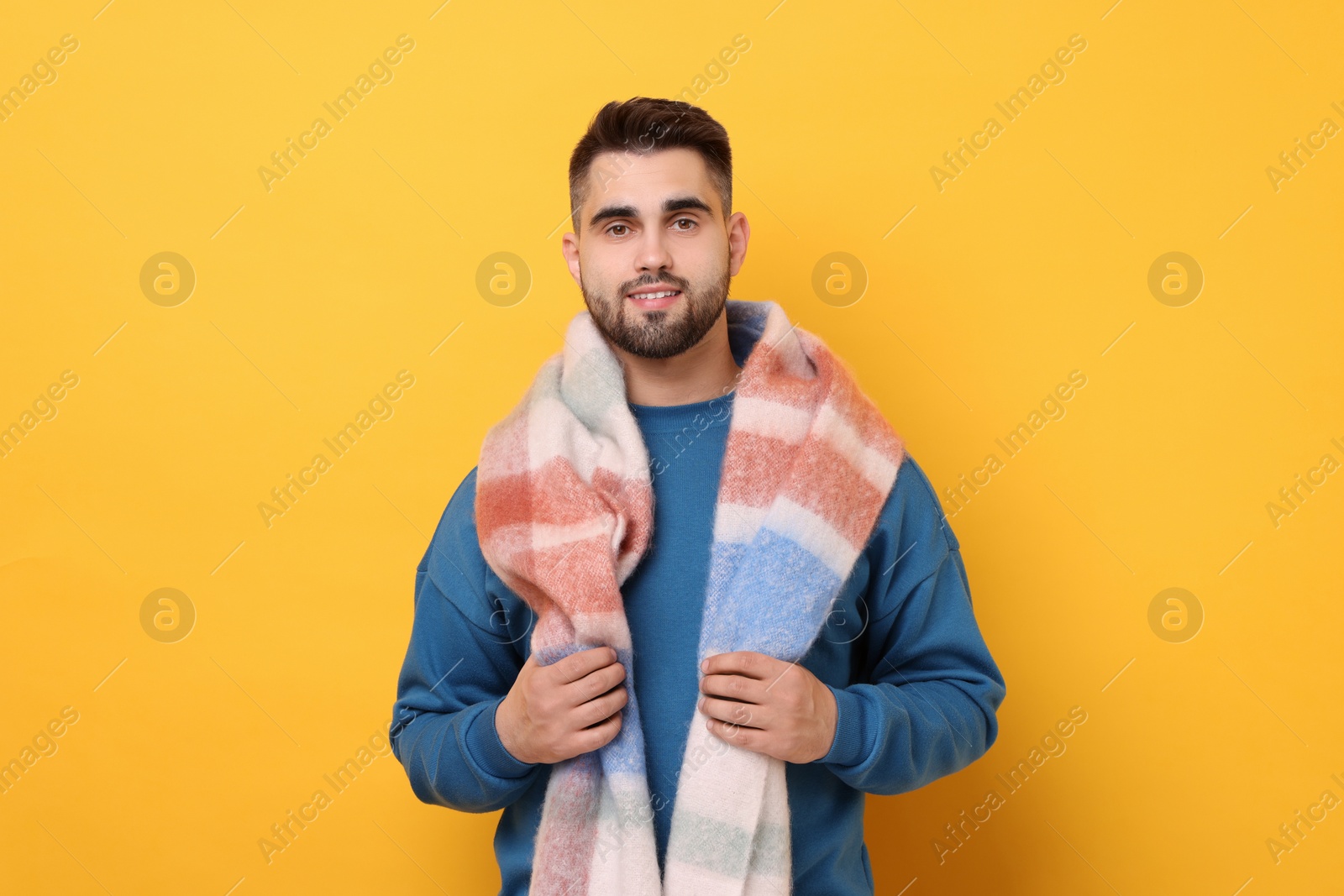 Photo of Smiling man in warm scarf on yellow background
