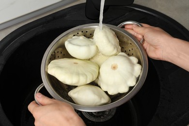 Photo of Woman washing pattypan squashes above sink, closeup