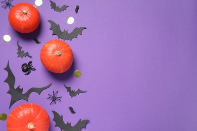 Flat lay composition with pumpkins, paper bats and spiders on purple background, space for text. Halloween decor