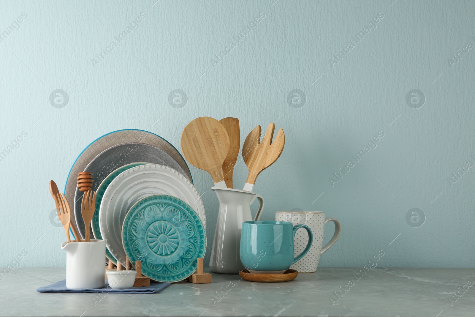 Photo of Set of kitchenware on grey marble table near light wall, space for text. Modern interior design