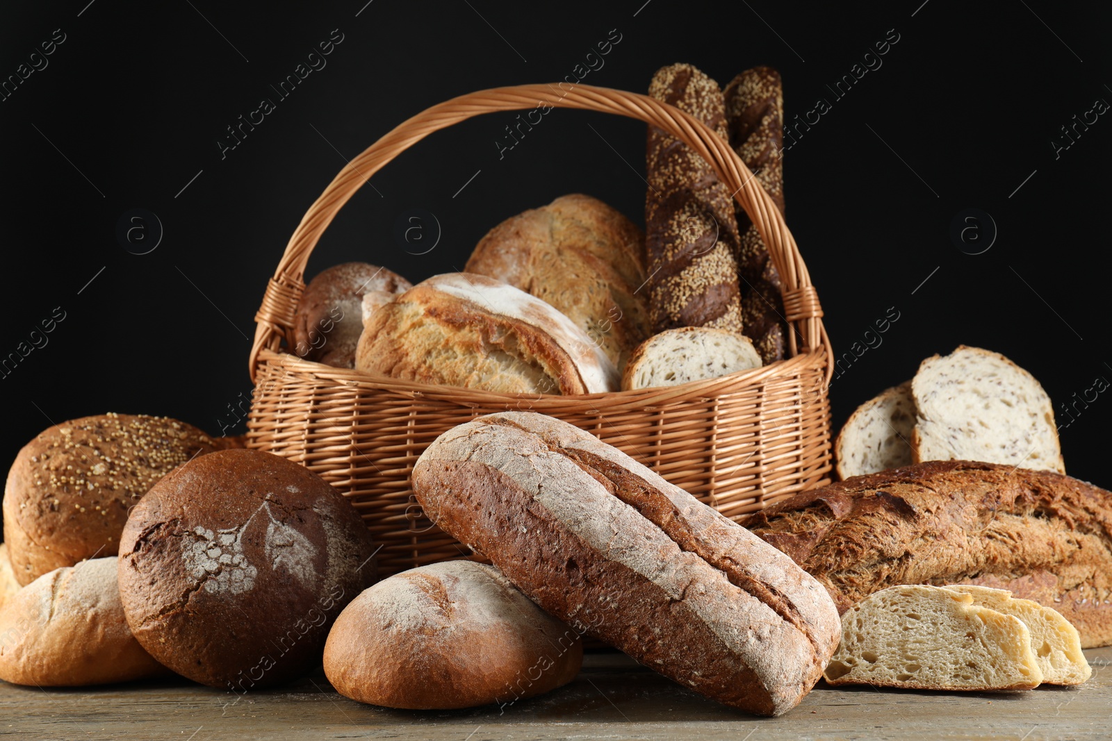 Photo of Wicker basket with different types of fresh bread on wooden table