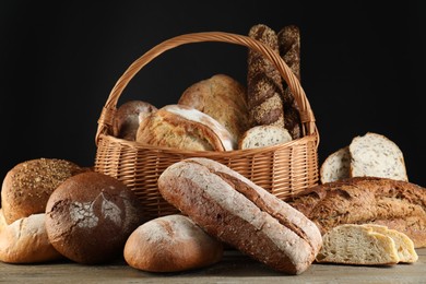 Wicker basket with different types of fresh bread on wooden table