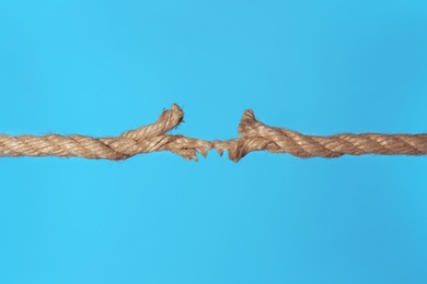 Photo of Stretched frayed rope breaking on color background