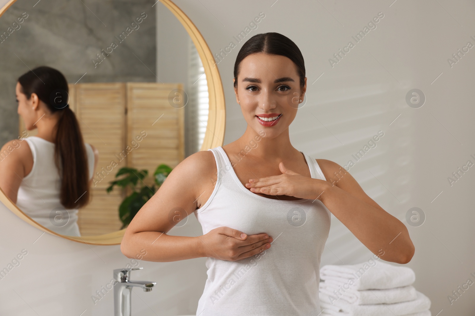 Photo of Beautiful young woman doing breast self-examination in bathroom