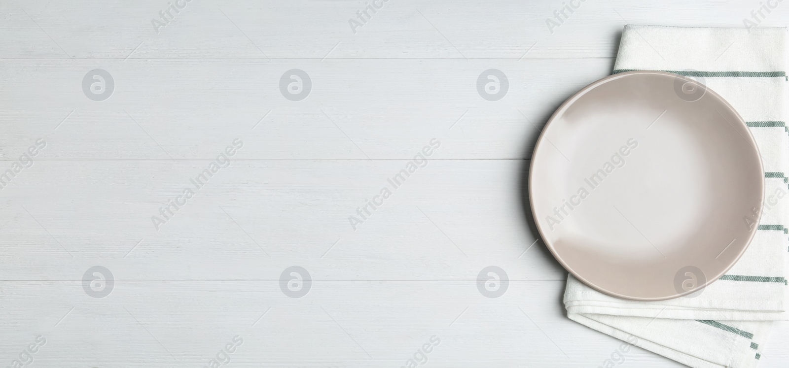 Photo of Empty grey plate and napkin on white wooden table, flat lay. Space for text