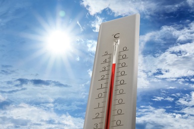 Image of Weather thermometer showing high temperature and blue sky with clouds on background