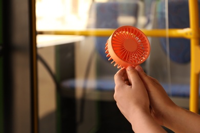 Photo of Woman with portable fan in bus, closeup. Summer heat