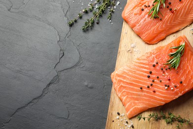 Fresh raw salmon and spices on black table, flat lay. Space for text