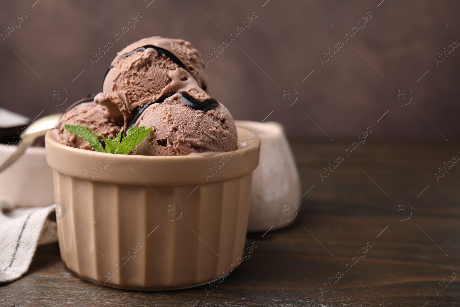 Photo of Bowl of tasty chocolate ice cream on wooden table, closeup. Space for text