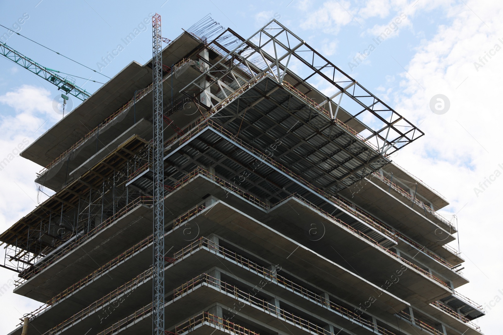 Photo of Multistory building under construction against cloudy sky, low angle view