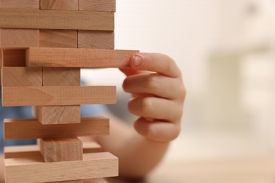 Child playing Jenga at home, closeup. Space for text
