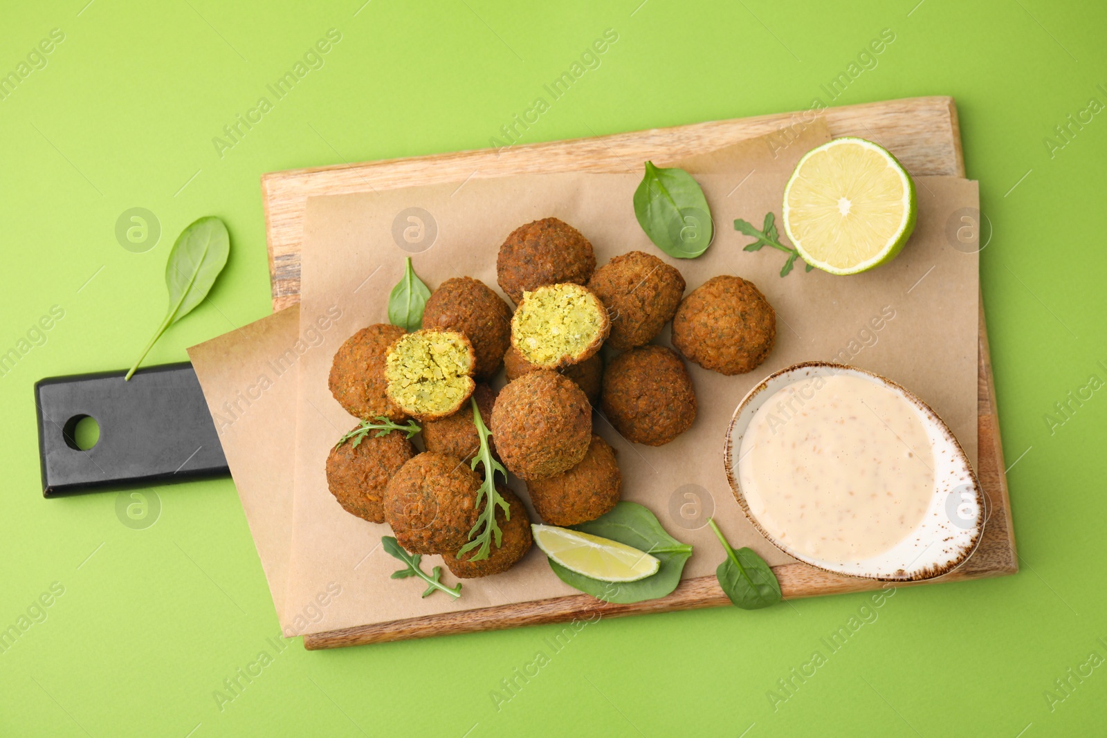 Photo of Delicious falafel balls served on green background, top view