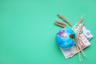 Photo of Import and export concept. Globe, ears of wheat and money on green background, flat lay with space for text