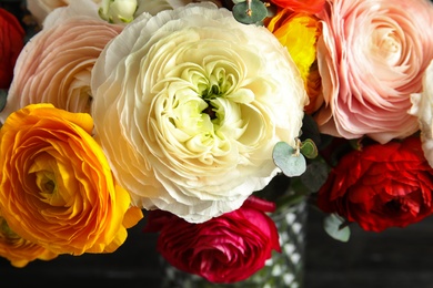 Photo of Bouquet with beautiful bright ranunculus flowers on dark background, closeup