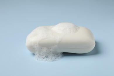 Soap and fluffy foam on light blue background