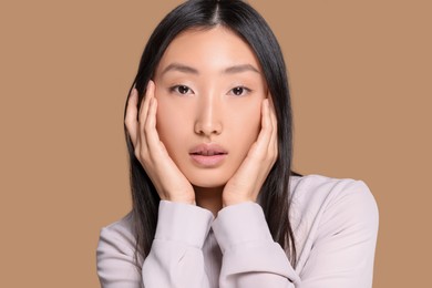 Portrait of beautiful young Asian woman in stylish outfit on beige background