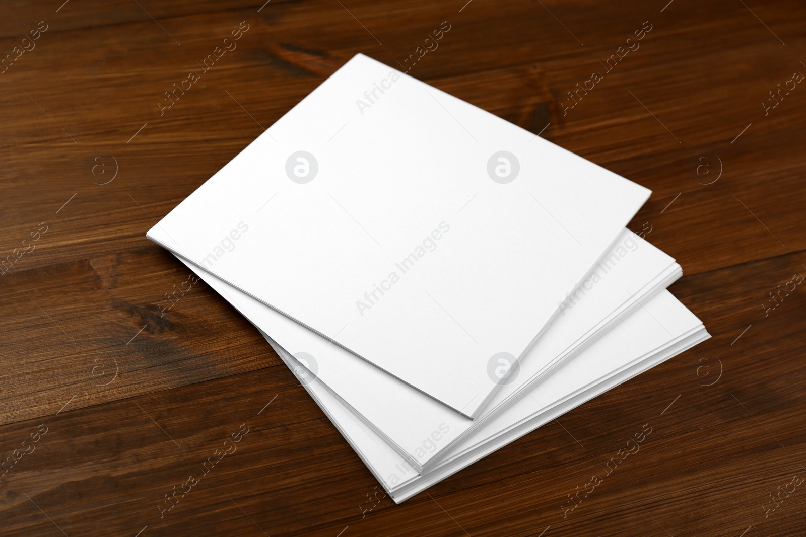 Photo of Stack of blank paper sheets on wooden table. Brochure design