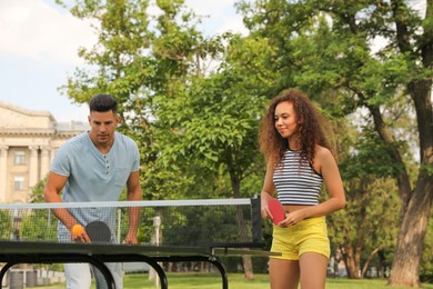 Photo of Friends playing ping pong outdoors on summer day