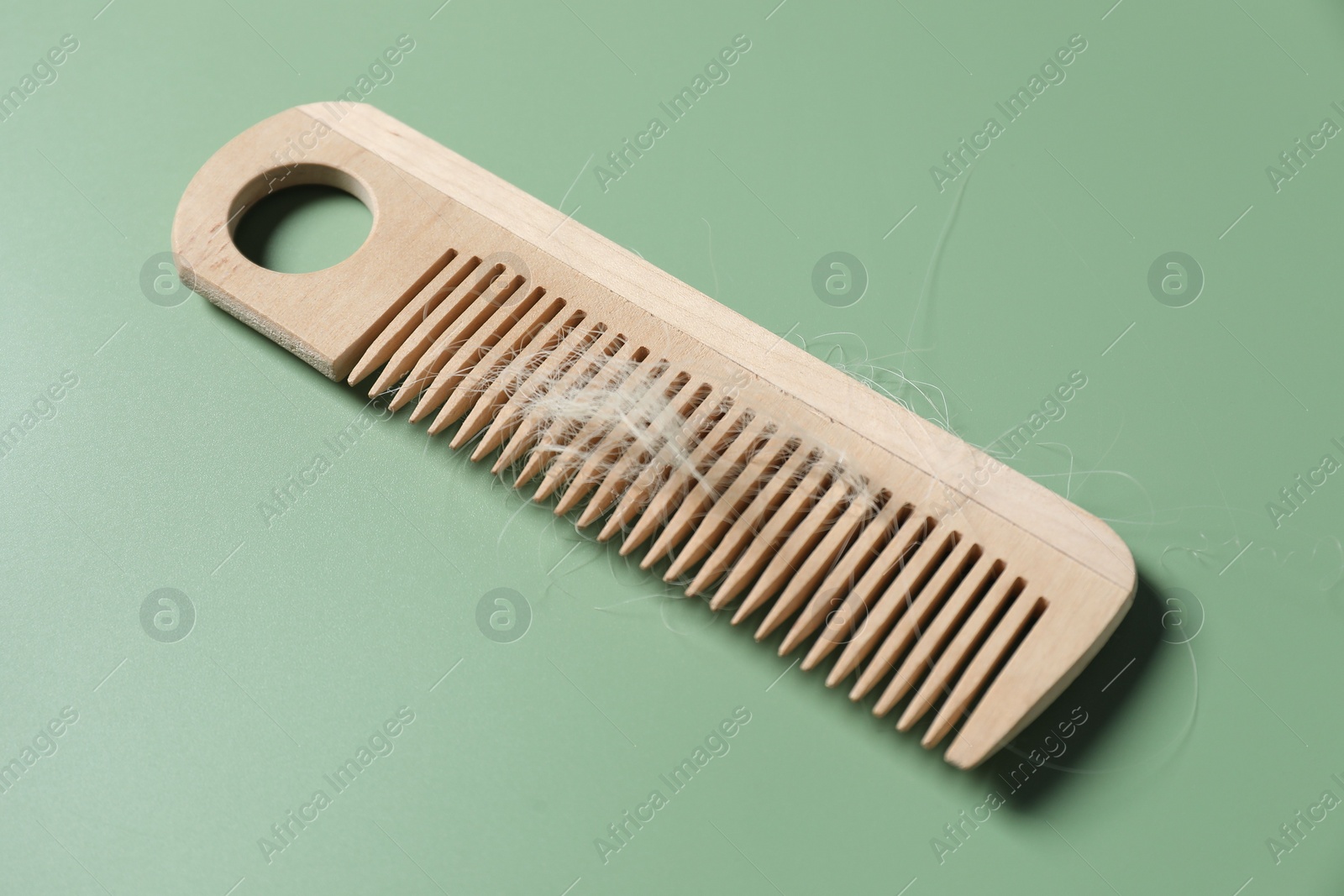 Photo of Wooden comb with lost hair on green background