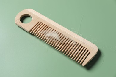 Photo of Wooden comb with lost hair on green background