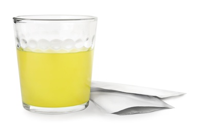 Glass of dissolved medicine and sachets on white background