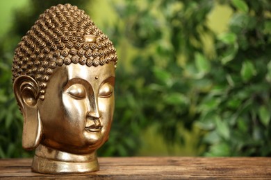 Photo of Buddha statue on wooden table. Space for text