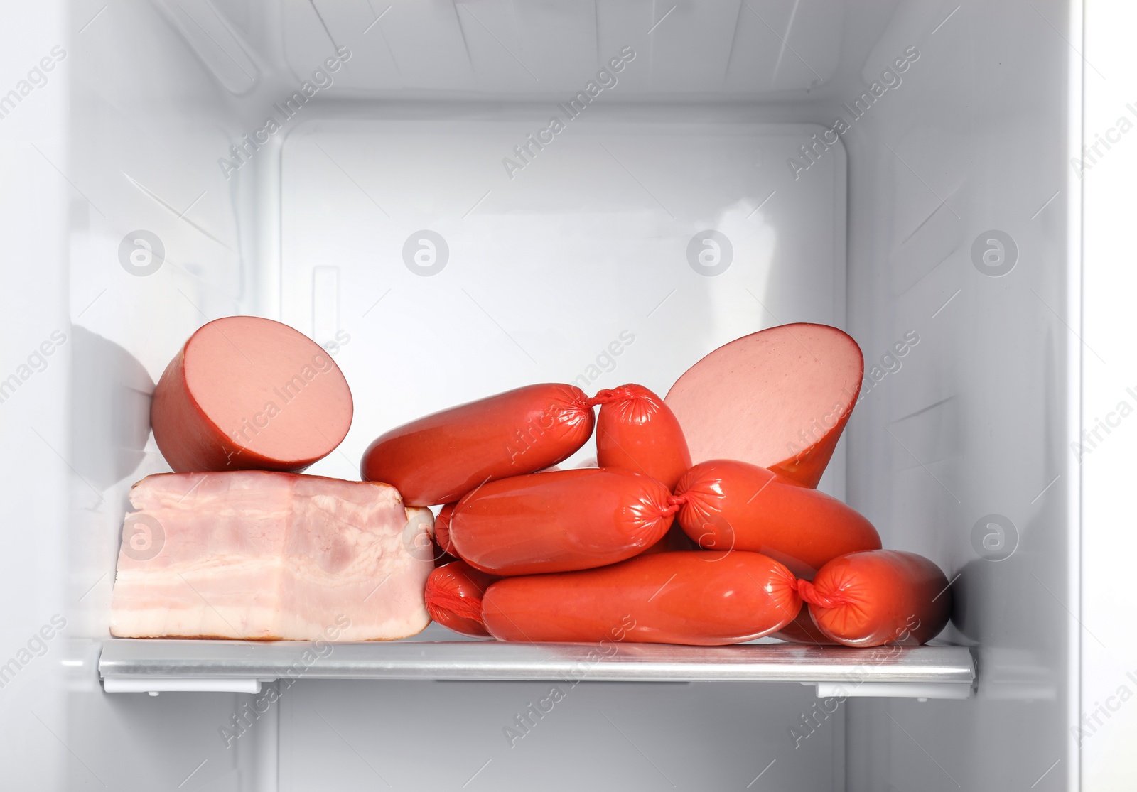 Photo of Delicious fresh sausages on shelf in refrigerator