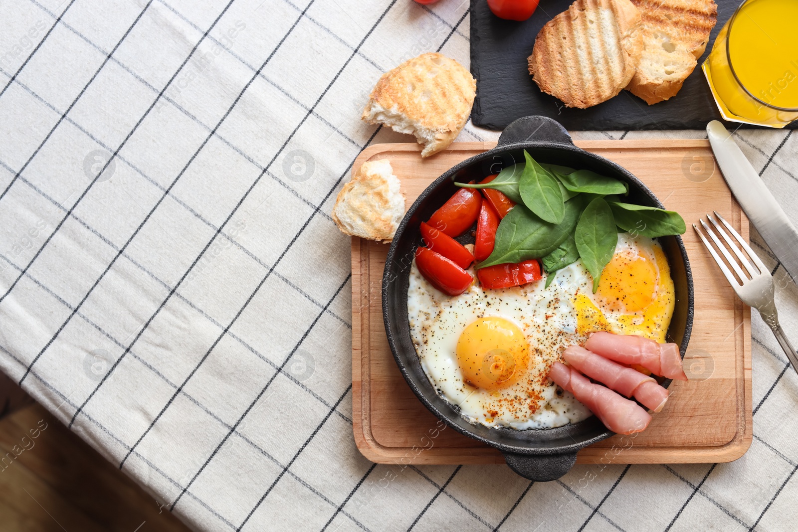 Photo of Delicious fried eggs with spinach, tomatoes and ham served on table, flat lay. Space for text